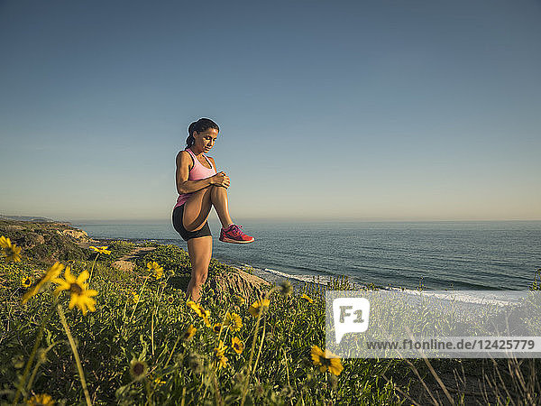 USA  Kalifornien  Newport Beach  Frau streckt sich auf Klippe