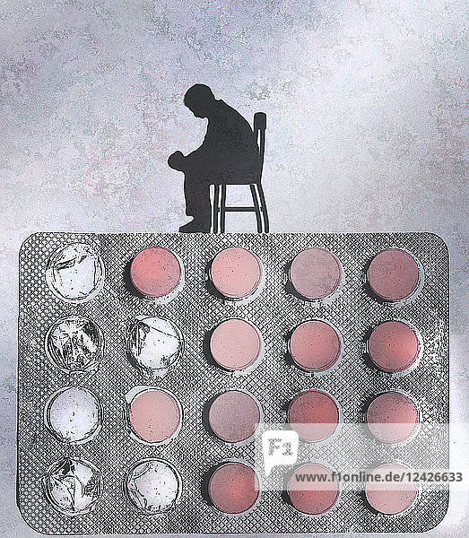 Depressed man sitting on top of pill blister pack