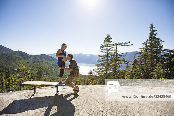 Side view of couple in natural setting with man kissing pregnant woman's stomach  Vancouver  British Columbia  Canada