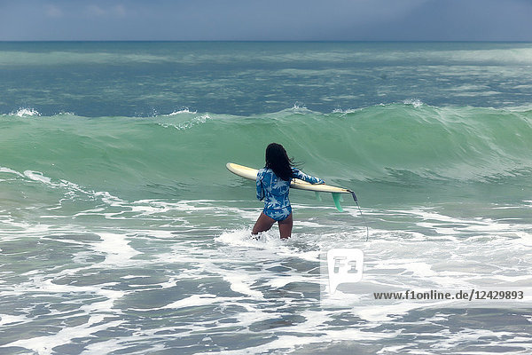 Rückansicht einer Frau mit Surfbrett im Meer