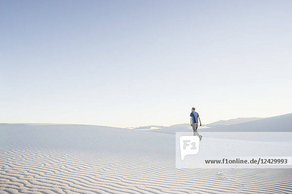 Distant view of lone man hiking in desert of White Sands National Monument  New Mexico  USA