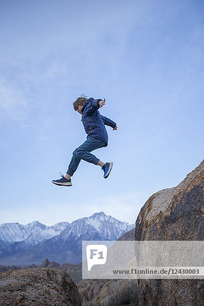 Side view shot of ten year old boy in mid-air after jumping from boulder  Alabama Hills Recreation Area  Lone Pine  California  USA
