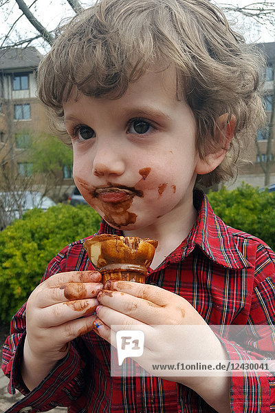 Junge mit schmutzigem Gesicht nach dem Verzehr von Schokoladeneis im Freien