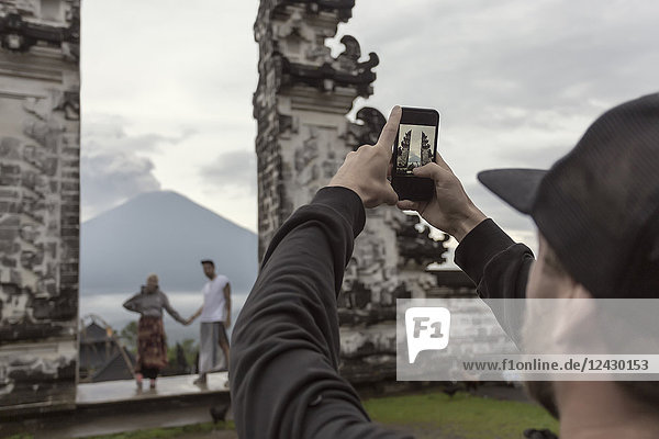 Blick über die Schulter eines Touristen  der ein Paar im Pura Lempuyang-Tempel fotografiert  Bali  Indonesien