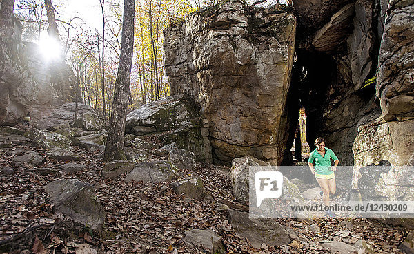 Front view of woman trail running in natural setting against rock formations in Moss Rock Preserve in Hoover  Alabama  USA