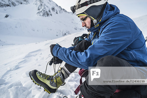 Seitenansicht eines Bergsteigers beim Binden der Schuhe in den Bergen im Winter  Tatra-Gebirge  Woiwodschaft Malopolskie  Polen