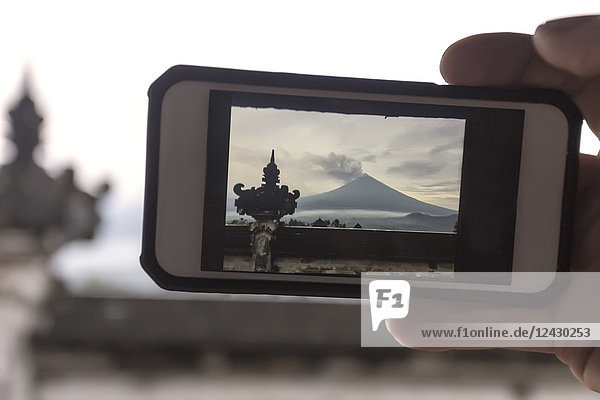 View of photograph on smartphone screen of Mount Agung volcano and Lempuyang temple  Bali  Indonesia