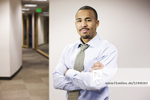 A portrait of a black businessman standing alone in his office space.