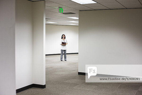 An Asian businesswoman standing alone in her office space.