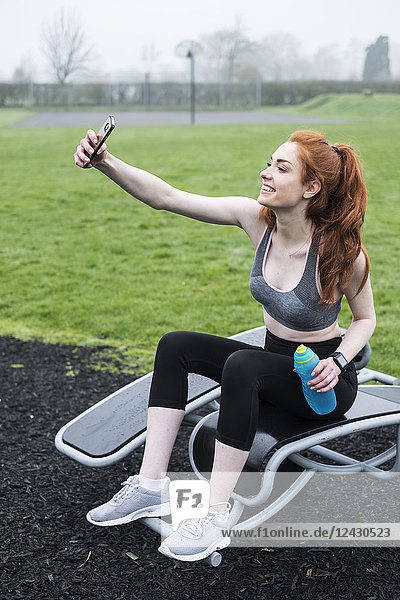 Lächelnde junge Frau mit langen roten Haaren in Sportausrüstung  die im Freien Sport treibt.