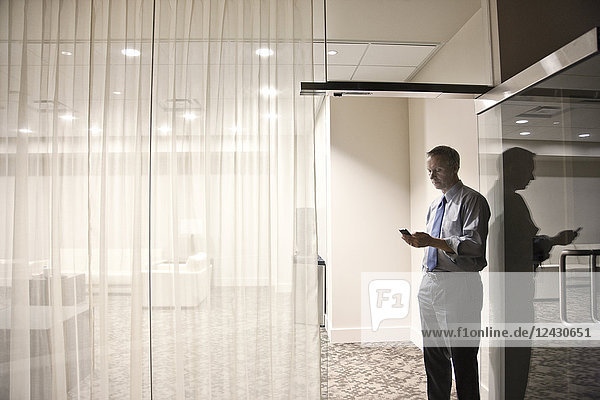 A view looking into a conference room of a businessman on his cell phone.