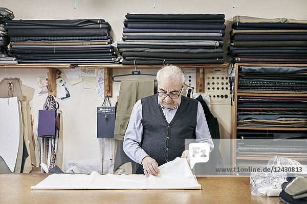 Man inspecting fabric in family-run tailor business