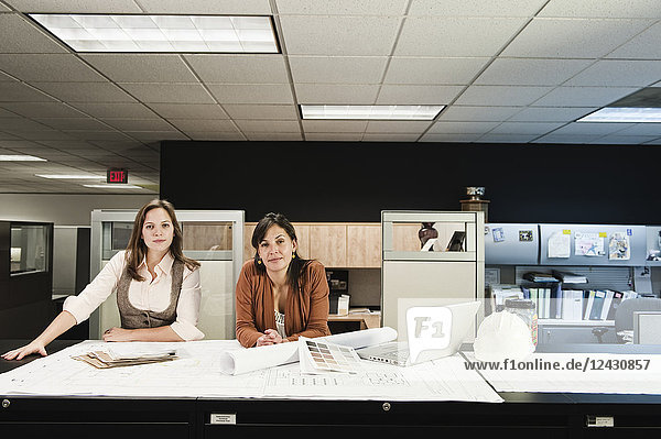 Frauen gemischter Rasse und Kaukasierinnen  die an einem Projekt an einem Tisch in ihrem Büro arbeiten.
