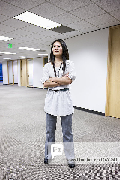 Eine asiatische Geschäftsfrau  die allein in ihrem Büro steht.
