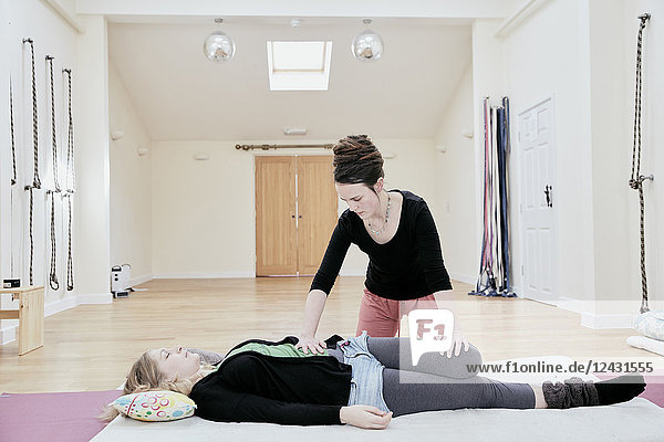 Woman lying down having a Thai massage  a masseur stretching her legs and knee joints.