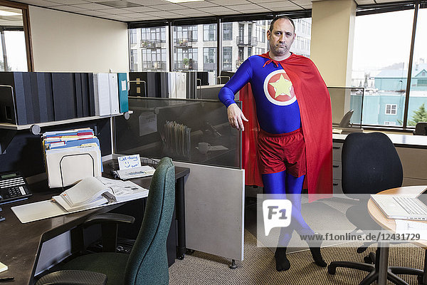Caucasian middle aged man super hero in his cubicle office.