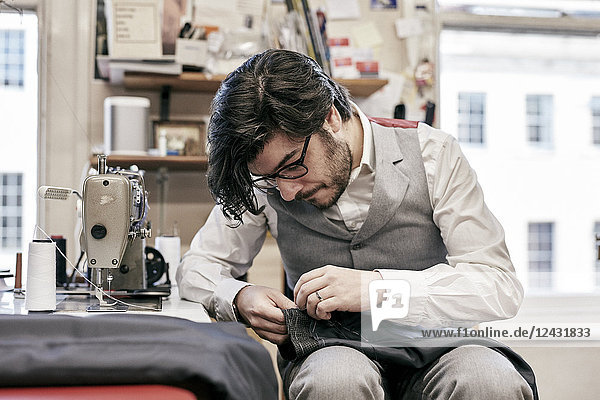Man sewing suit by hand in family tailor business