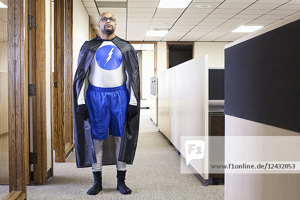 A black businessman office super hero standing in an office hallway.