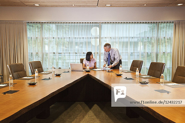 Asian businesswoman and Caucasian businessman meeting in a conference room