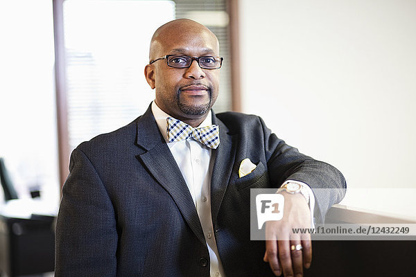 A portrait of a black businessman in a suit and bow tie.