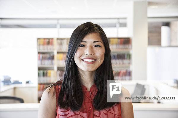 Das Porträt einer asiatischen Geschäftsfrau in ihrem Büro  die in die Kamera schaut.