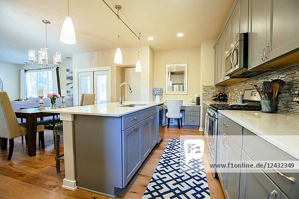 Moderne Wohnküche mit grün-grauen Einbauschränken  einer Kücheninsel und blauem Teppichboden.