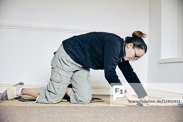 Frau schneidet mit dem Messer Teppiche auf dem Boden ab