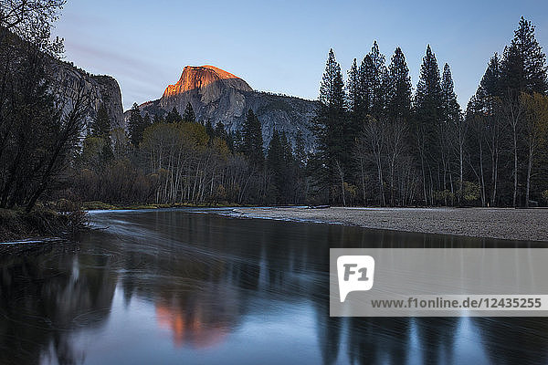 Der Half Dome fängt das letzte Licht des Sonnenuntergangs ein  das sich im Merced River im Yosemite-Nationalpark spiegelt  UNESCO-Welterbe  Kalifornien  Vereinigte Staaten von Amerika  Nordamerika