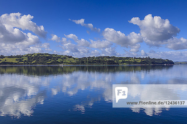 Reflexionen in der Castro-Bucht  ländliche Szene  flauschige Wolken und sanfte Hügel  Isla Grande de Chiloe  Chilenische Seenplatte  Chile  Südamerika