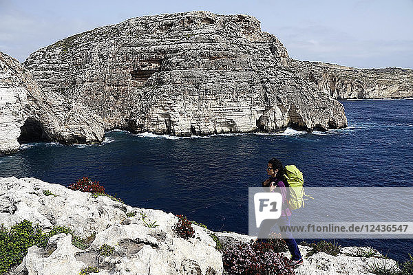 Eine Frau wandert oberhalb der Meeresklippen in der Nähe der Blauen Grotte  Süd-Malta  Mittelmeer  Europa