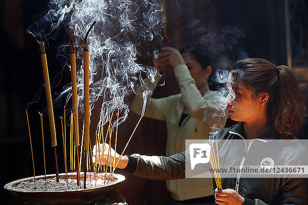 Taoist temple  Emperor Jade pagoda (Chua Phuoc Hai)  Buddhist worshipper burning incense sticks  Ho Chi Minh city  Vietnam  Indochina  Southeast Asia  Asia