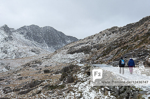 Hikers on the Miner's Track at base of Mount Snowdon in a wintry landscape in the Snowdonia National Park  Gwynedd  Wales  United Kingdom  Europe