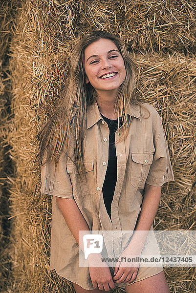 Beautiful young woman standing in front of hay bales  portrait