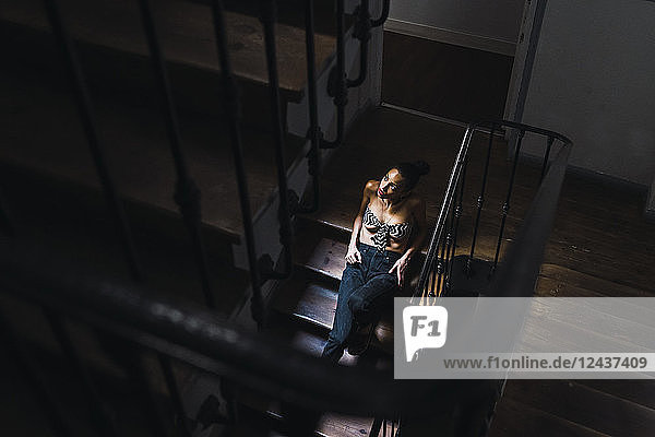 Beautiful young woman sitting in staircase in sunlight