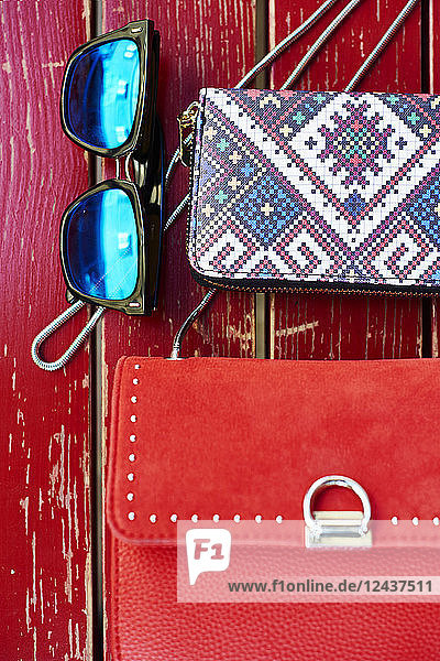Sunglasses  purse and handbag on red wooden bench