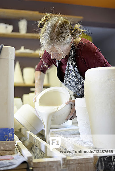 Woman pouring liquid into mold in porcelain workshop
