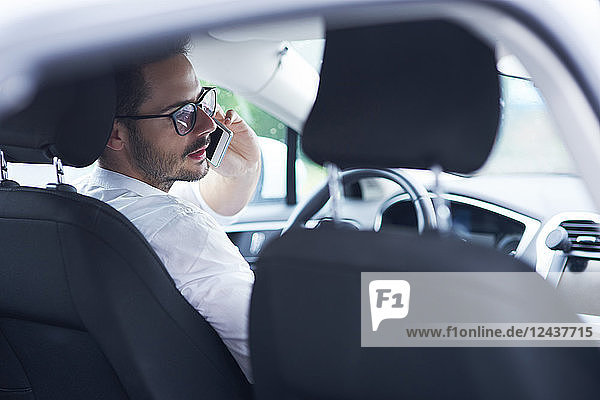 Businessman sitting in car talking on the phone