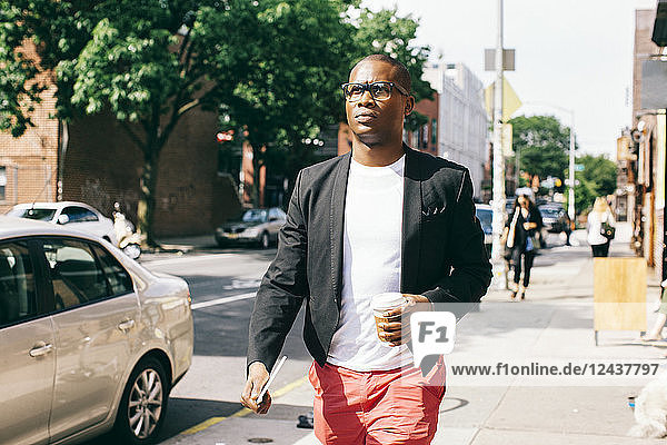 USA  NYC  Brooklyn  Man walking in the street  holding cup of coffee