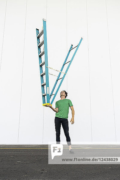 Acrobat balancing ladder upside down in his hand