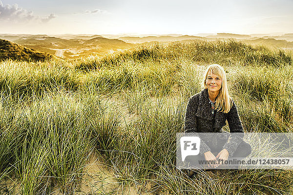Portrait of smiling woman sitting in dunes