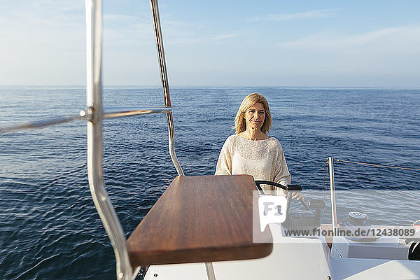 Mature woman navigating catamaran on a sailing trip
