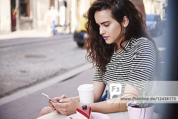 Young woman using cell phone at outdoor cafe in the city