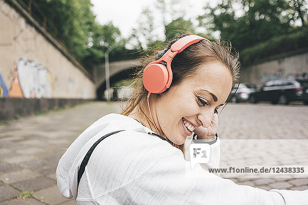 Smiling sportive young woman wearing headphones outdoors