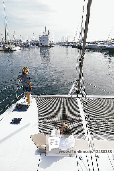 Couple on a catamaran  man sitting and reading book