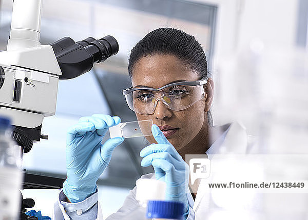 Female scientist examining a human sample on a microscope slide
