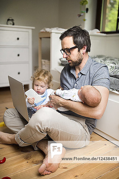 Father with his little son and baby daughter working from home
