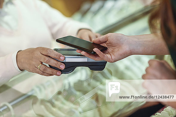Close-up of woman paying with smartphone in a store