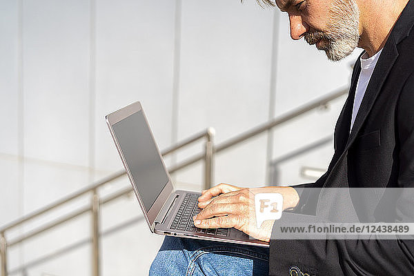 Businessman sitting outdoors using laptop