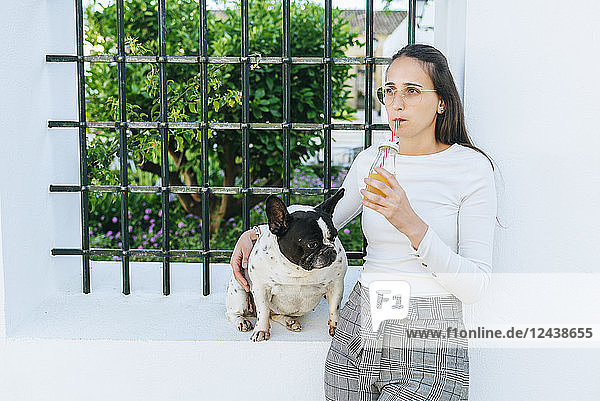 Woman drinking juice  with her dog outside