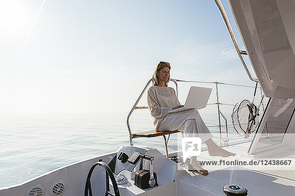 Woman sitting on catamaran  using laptop
